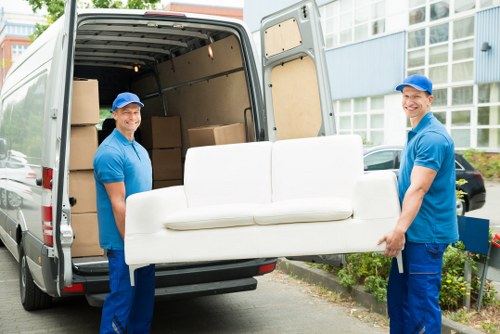 Open moving van parked outside a Merton terrace, workers loading boxes