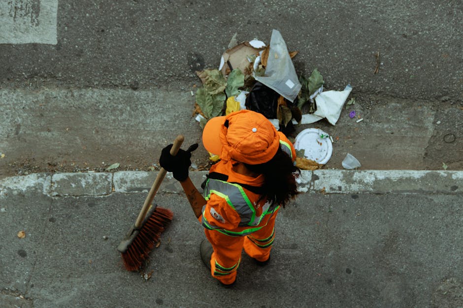 Three construction workers wearing high-visibility yellow vests and white safety helmets are standing outside on a sidewalk near a street, engaged in a discussion during a home relocation or building